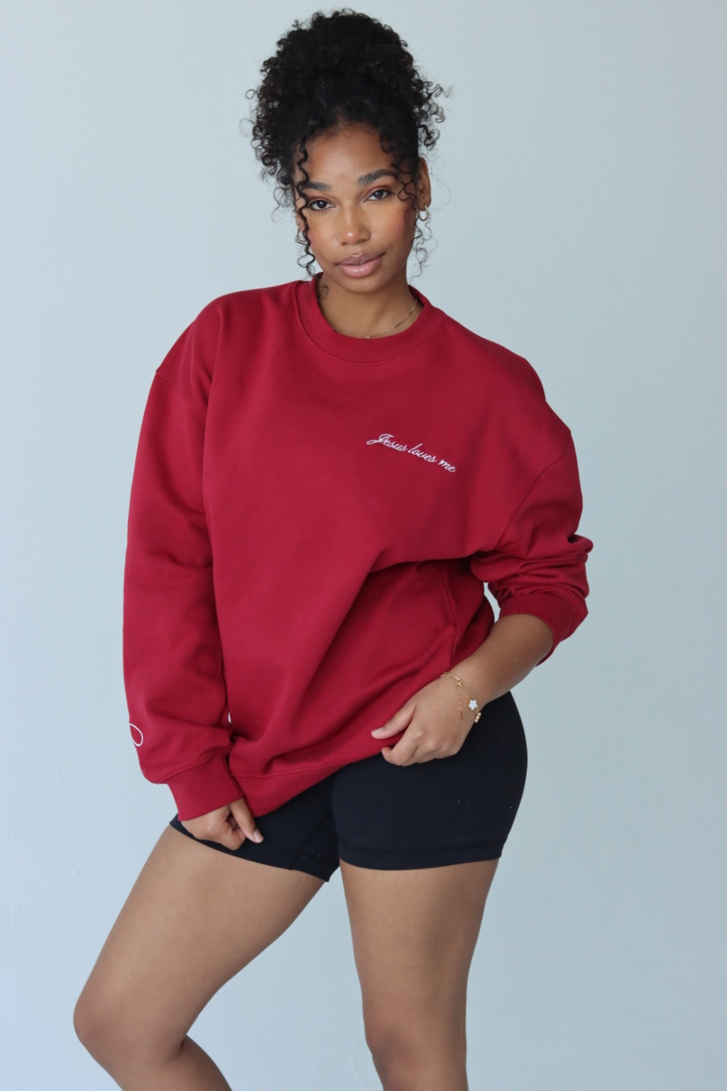 Person wearing a red sweatshirt with text and matching pants on a plain background