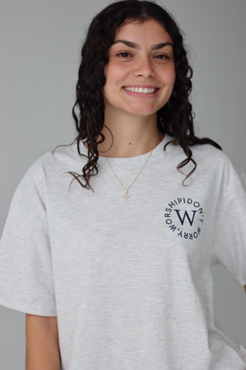 Woman wearing a white oversized t-shirt and black shorts on a gray background